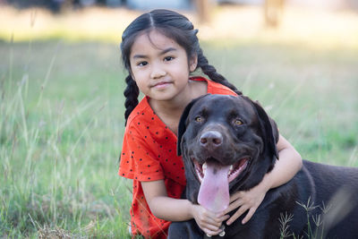 Portrait of girl with dog on field