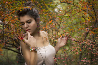 Close-up of young woman standing by tree during autumn