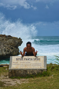 Portrait of young man by sign at beach