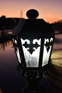 Close-up of silhouette man by lake against sky during sunset