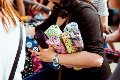 Midsection of woman holding fabric rolls at market stall