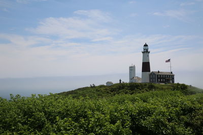 Lighthouse on hill against cloudy sky