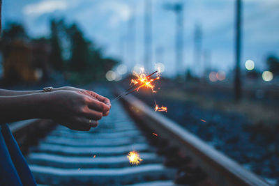 Close-up of hands holding illuminated sparklers at night