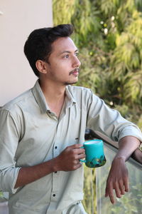 Young man looking away while sitting outdoors