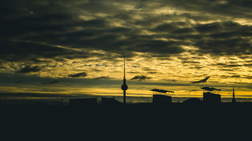 Silhouette of tower against cloudy sky during sunset