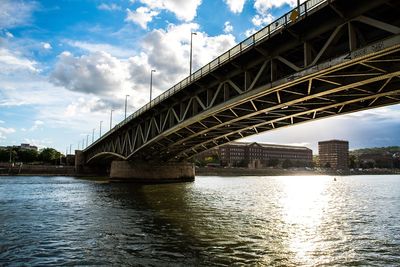 Low angle view of bridge over river against cloudy sky