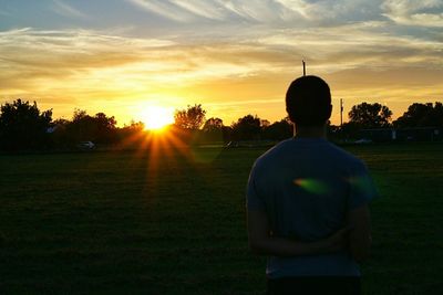 Scenic view of grassy field against sky at sunset