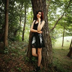 Portrait of young woman standing against trees