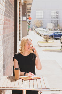 Young woman using mobile phone while sitting on table