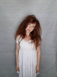 Portrait of young woman standing against wall