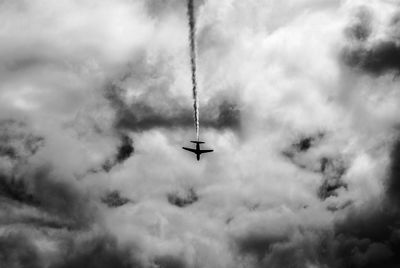 Low angle view of airplane flying in cloudy sky