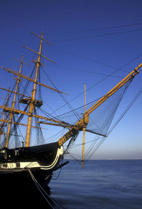 Sailboat in sea against clear blue sky