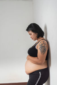 Side view of woman standing against wall