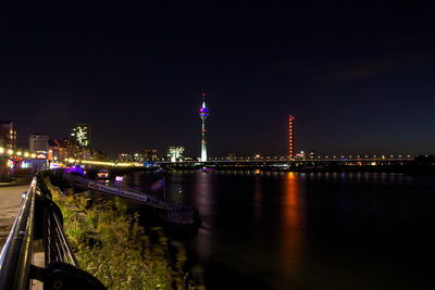 Illuminated bridge over river with city in background