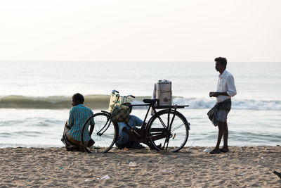 Rear view of man riding bicycle on beach