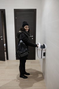 Portrait of smiling woman drying hand in bathroom