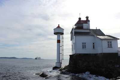 Lighthouse by sea against sky