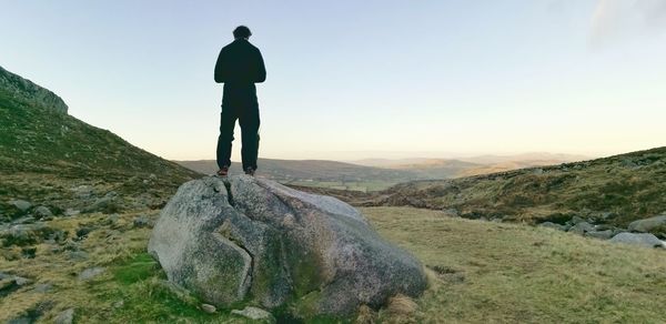 Rear view of man on boulder against sky