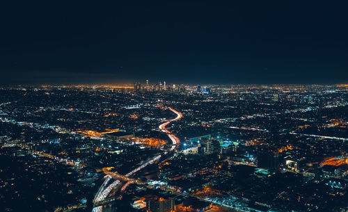 Aerial view of illuminated highway amidst buildings in city at night