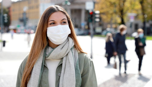 Close-up of young woman wearing mask in city during winter