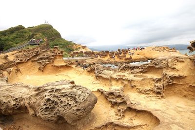 Rock formations on shore against sky