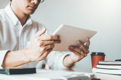 Midsection of man using mobile phone while sitting on table