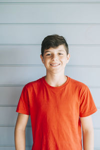 Portrait of smiling boy standing against wall