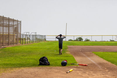 Rear view of man standing on grassland against clear sky