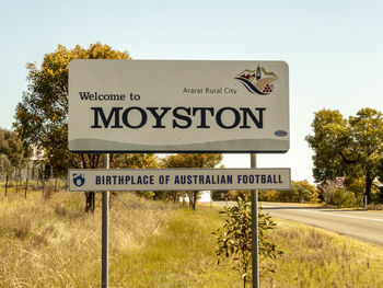 Information sign by road against sky