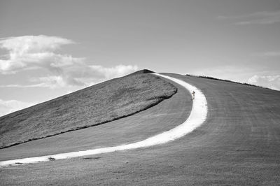 Road leading towards hill against sky