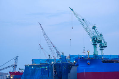 Cranes at commercial dock against sky