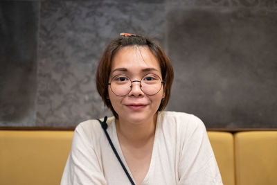 Portrait of smiling young woman against wall