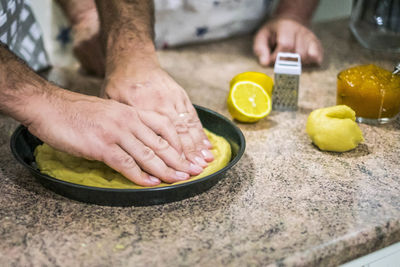 Cropped hands of man kneading dough in plate