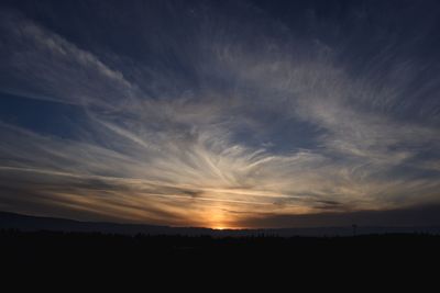 Scenic view of dramatic sky over silhouette landscape