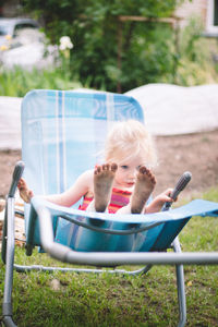 Full length of cute girl relaxing on chair outdoors