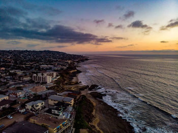 Aerial view of townscape by sea against sky during sunset