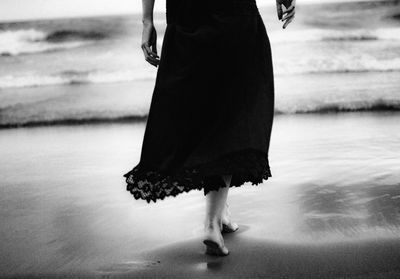 Low section of woman standing on beach against sky