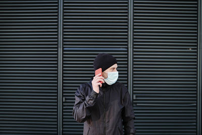 Person holding umbrella standing against wall