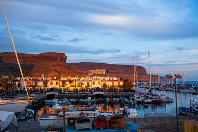 Boats moored in harbor at dusk