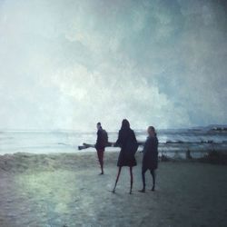 Rear view of people on beach against sky
