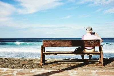 Man sitting on bench at the seaside