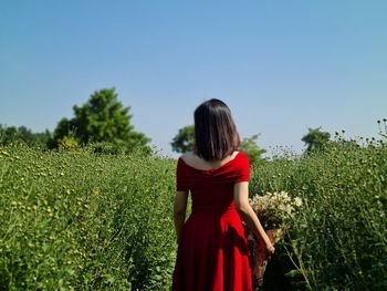 Rear view of woman standing on field against clear sky