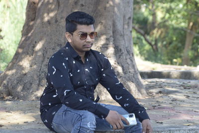 Young man wearing sunglasses sitting outdoors