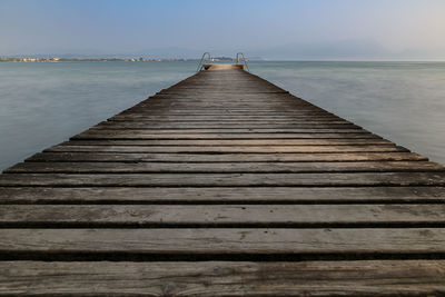 Wooden pier over sea against sky