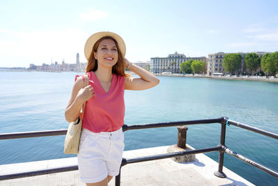 Portrait of woman standing against railing