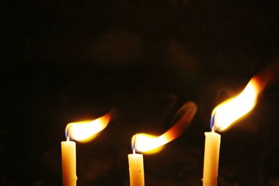 Close-up of lit candles in darkroom