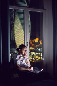 Side view of woman using mobile phone while sitting at home