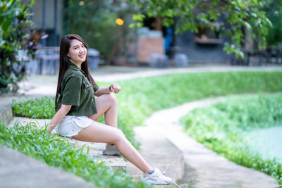 Portrait of young woman sitting on footpath