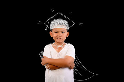 Portrait of smiling boy standing against black background