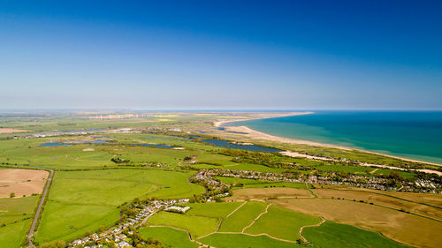 Scenic view of agricultural field by sea against sky